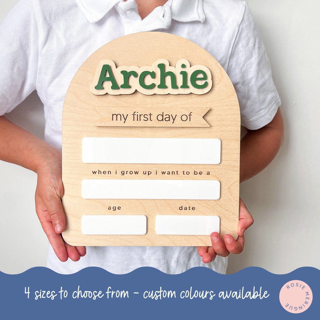 Child holding a wooden plaque with 'Archie' and space for writing, against a plain background.