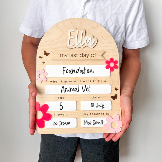 Child holding a wooden board with 'Ella' on it, personalized for her last day of Foundation.
