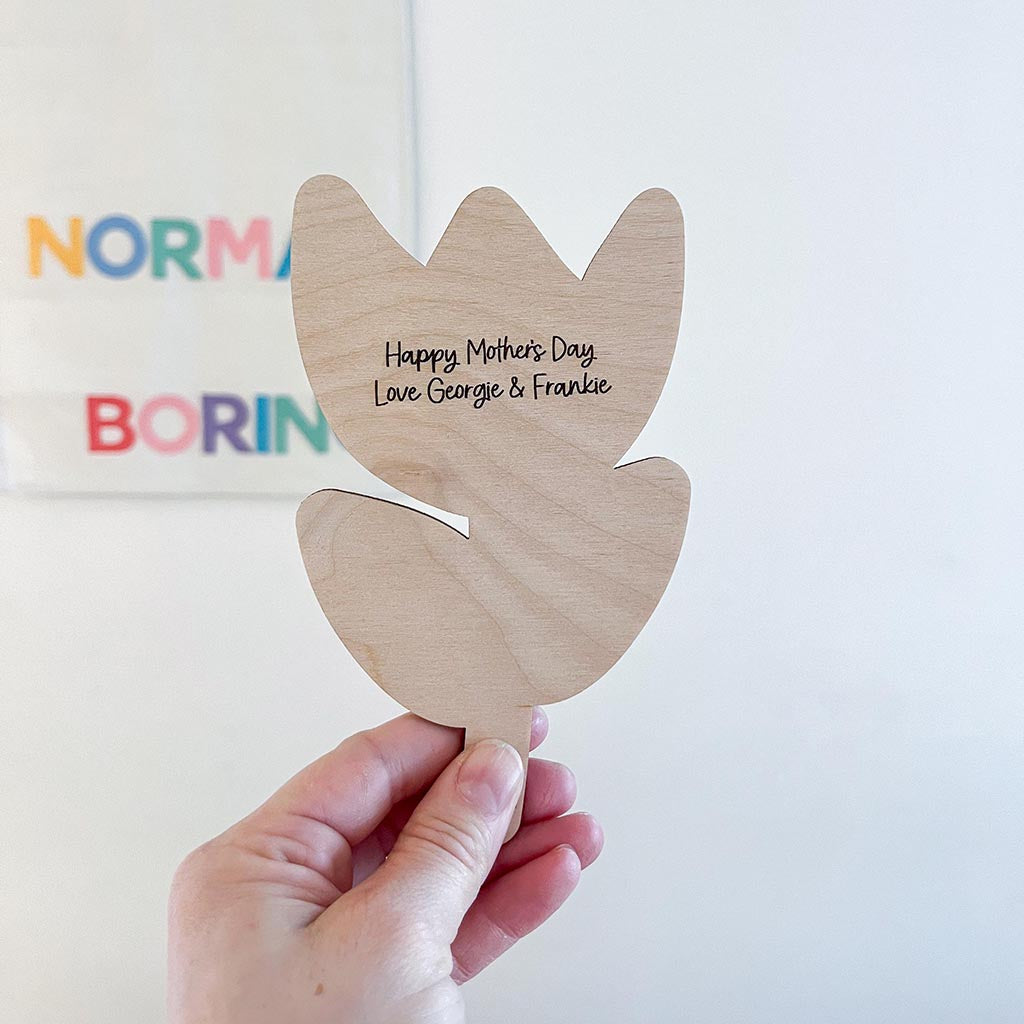 Wooden tulip-shaped card with 'Happy Mother's Day' text, held by a hand against a light background.