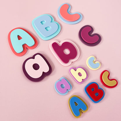 Colourful acrylic alphabet magnets arranged on a pink background