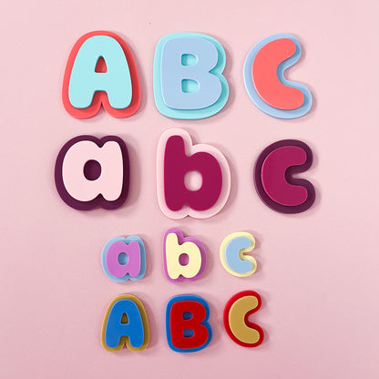 Three rows of colorful alphabet letters for children, showing uppercase and lowercase letters A, B, and C in various pastel and bright colors, arranged on a solid pink background.