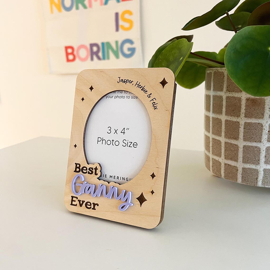 Wooden photo frame with 'Best Grammy Ever' text on a light surface with a plant in the background.