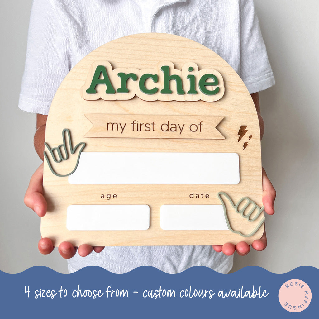 Wooden plaque with 'Archie' and placeholders for age and date, held by a person.