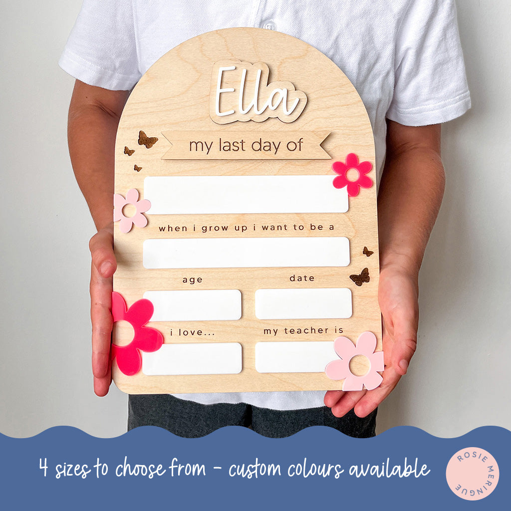 Wooden board with cutouts held by a person, personalized for 'Ella's last day of school'.