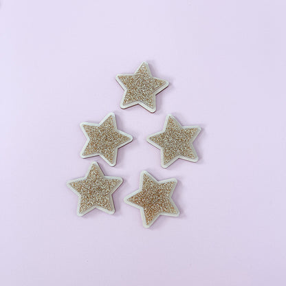 Gold glitter star wall decor displayed beside a framed children's print