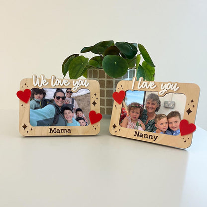 Two wooden photo frames with family photos and decorative hearts on a light surface.