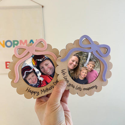 Two wooden photo frames with decorative bows held by a hand, featuring family photos and text.