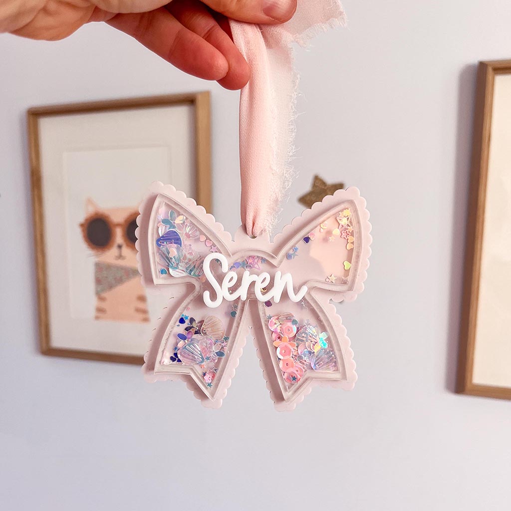 Decorative acrylic bow with glitter inside and the name 'Seren' on a light background