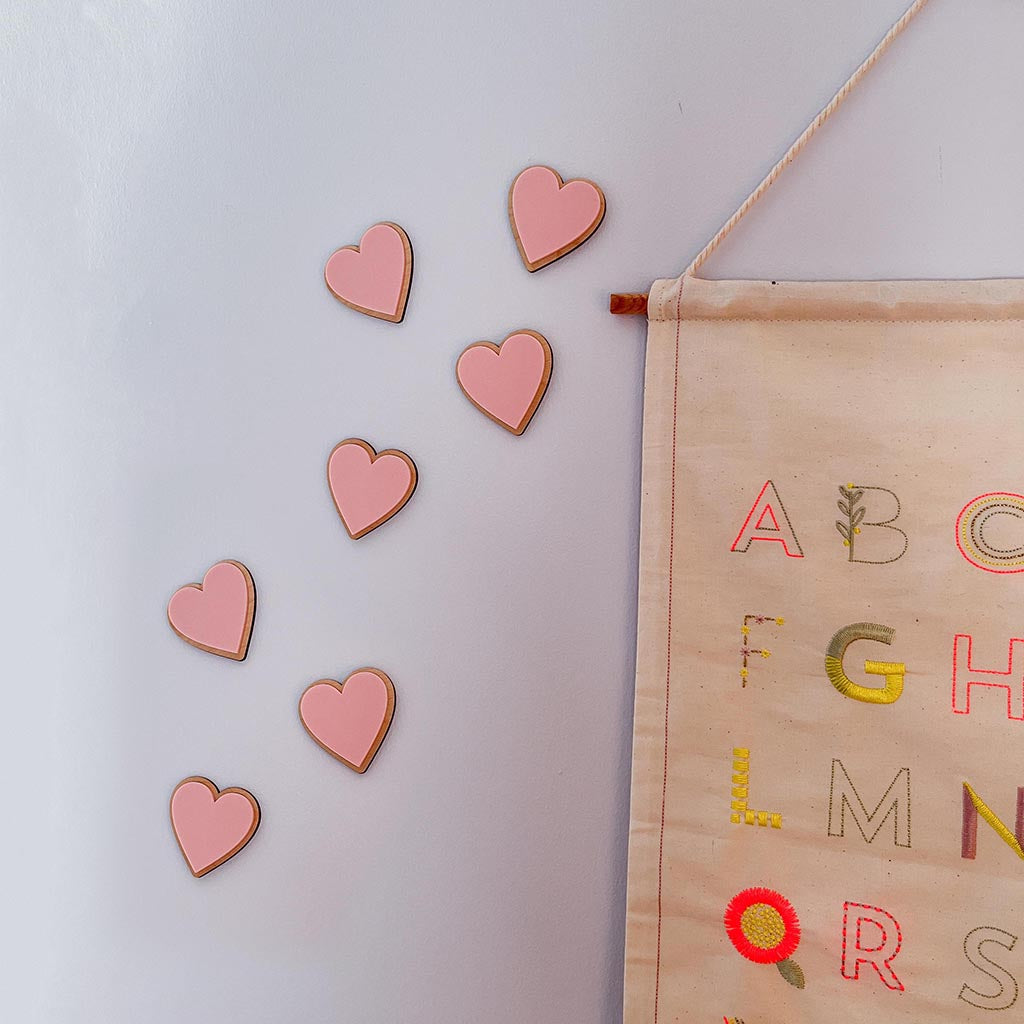 Pink acrylic heart wall decorations layered onto natural wood