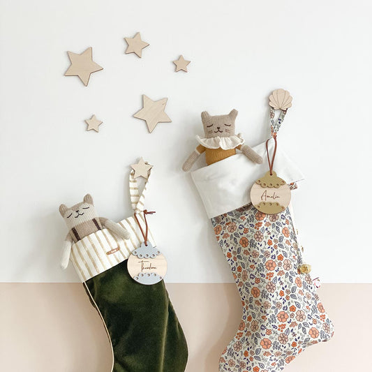 Natural wooden star decorations styled above children's Christmas stockings
